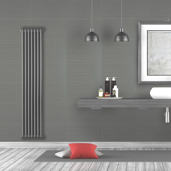 Modern bathroom interior with grey walls, vertical radiator, industrial pendant lights, floating vanity with toiletries, minimalist artwork, and red accent cushion on floor.