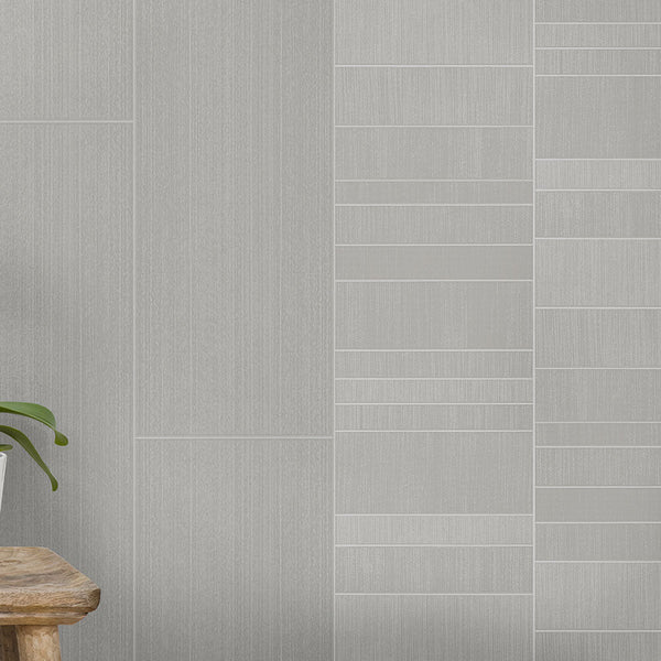 Modern minimalist interior wall design with textured gray wallpaper, contrasting patterns, wooden stool, and green houseplant leaf peeking in from corner