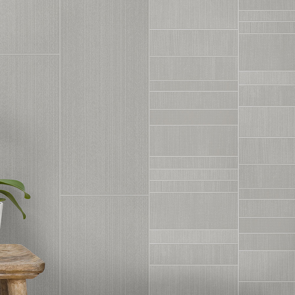 Modern gray tile wall with different textures, wooden stool, and green houseplant on light gray flooring