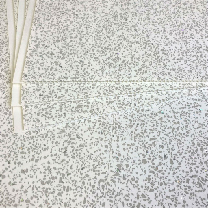 Terrazzo flooring texture with random speckled pattern and white PVC pipes laying on the surface