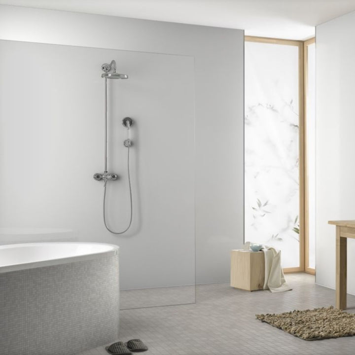 Modern bathroom interior with tiled bathtub, glass shower, wooden stool, beige towel, flip-flops, and natural light coming through the window with white floral pattern curtain.